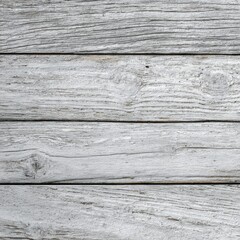 Weathered gray wood planks arranged horizontally, showing grain and texture.  The wood appears aged and possibly painted white, with visible knots and imperfections