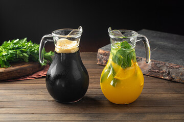 Kvass and lemonade in glass jugs on wooden table in restaurant