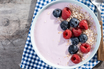 Healthy smoothie bowl with berries on wooden table