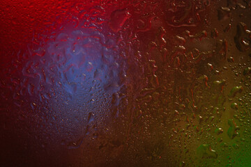 Wet glass. Drops of water on dark glass. Abstract texture. Colored spots of light