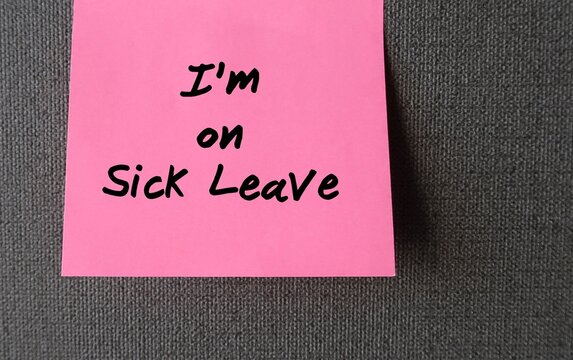 Office wall with stick note written I'M ON SICK LEAVE -  Employee takes time away from work of illness -note worker left to inform he is absent from job due to an illness, injury or accident
