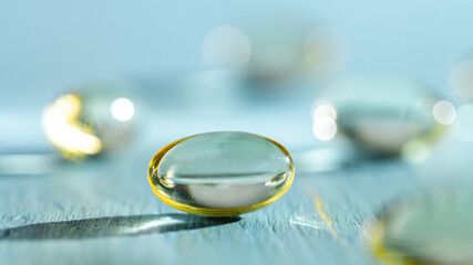 Softgels and fish oil, vitamin D capsules reflecting light against a blue background, creating a stunning bokeh effect while highlighting the importance of health and wellness in daily nutrition