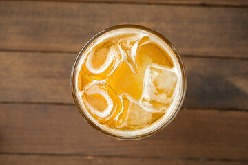 Glass of cold lemonade with ice cubes on wooden table