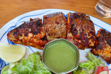 Tandoori trout fish grilled to perfection, served with tangy green chutney, lemon wedge, and fresh green salad. A flavorful Indian dish ideal for seafood lovers. Great for healthy meals.
