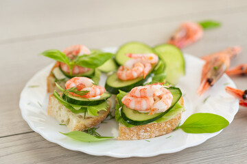 Delicious portioned appetizers with shrimps and greens on a wooden table