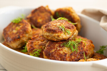 Delicious fried cutlets in a baking dish on a white table