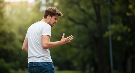 man turning away in anger. Young man gesturing while talking in a park during daytime 