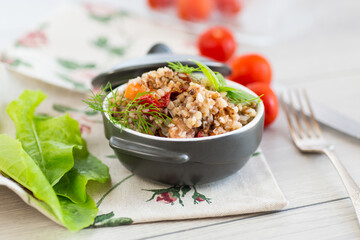 boiled buckwheat with vegetables in a ceramic bowl on a wooden table