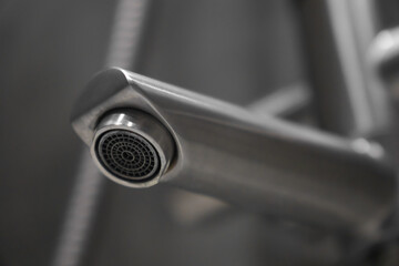 Close-up of a contemporary chrome faucet spout, showcasing its sleek design and highlighting the...