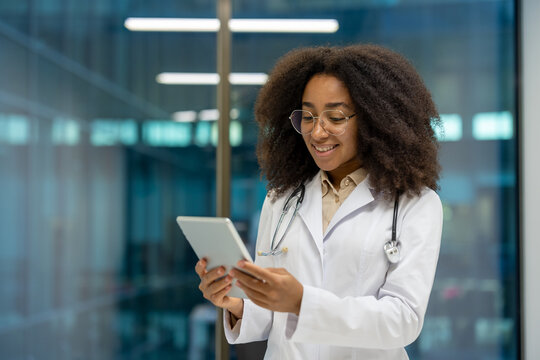 A smiling female doctor examines a tablet in a modern medical setting, reflecting a blend of technology and care.