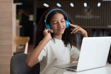 African American male student or kid studying online by using laptop computer and wearing headphone...