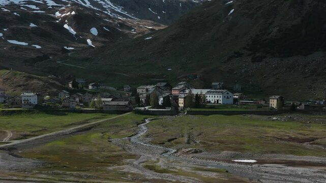 Montespluga village in Italian Alps, mountain valley, small stream, Lombardy, Italy. Aerial drone lateral view