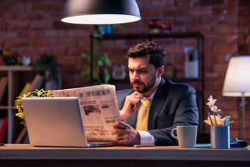 Executive reads business paper at desk, showing focus, awareness, and interest in financial updates