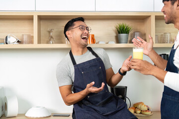 Couple Sharing a Drink. Men laughing and enjoying beverages in a modern kitchen.