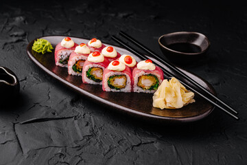 Delicious sushi rolls served on a dark plate with wasabi and ginger