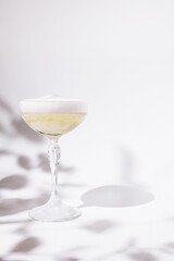 Elegant cocktail served in a clear glass with a frothy top in soft light