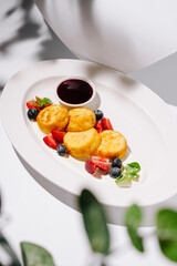 Delicious pancakes garnished with fresh berries and syrup on a white platter