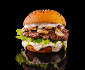 Gourmet burger with lettuce, mushrooms, and creamy sauce on black