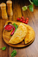 Delicious homemade calzones served with fresh ingredients on wooden board
