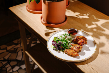 Delicious chicken wings served with fresh salad and rice on wooden table