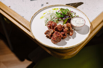 Tasty grilled meat with fresh herbs and sauce at a cozy spot