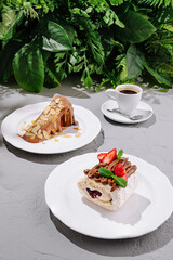 Delicious desserts served on plates with coffee in a lush green setting