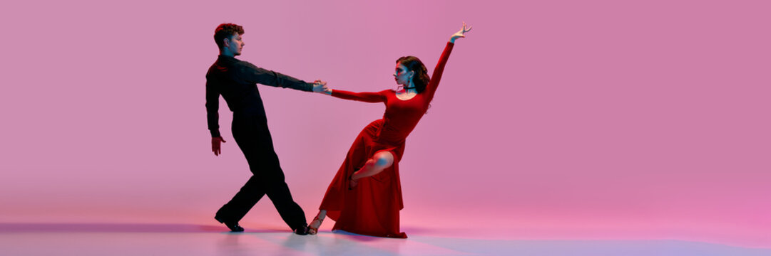 Argentine tango dancers strike a dramatic pose against a pink gradient background. Concept of passion, elegance, and cultural expression in dance photography. Banner