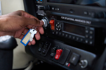 Pilot inserting key in ignition switch of aircraft cockpit panel
