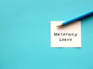 On blue copy space background - Pencil wrote on note Maternity Leave - period in which female employees allowed to absent from work before and after she gives birth - to take care of newborn child