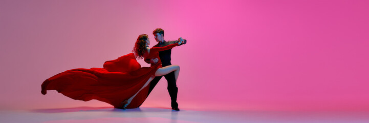 Argentine tango dancers are embracing against a pink studio background. Concept of passionate dance...