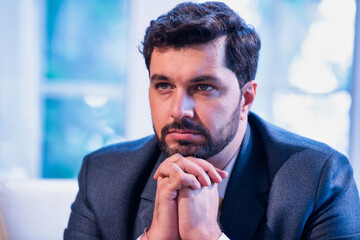 Indian businessman thinking seriously while seated on office couch, symbolizing focus and planning