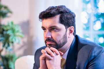 Indian businessman thinking seriously while seated on office couch, symbolizing focus and planning