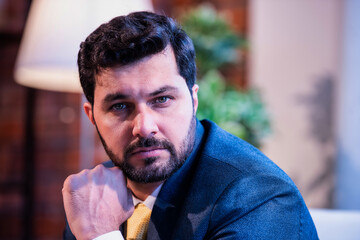 Indian businessman thinking seriously while seated on office couch, symbolizing focus and planning