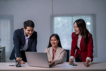 Three people are sitting at a desk with a laptop open