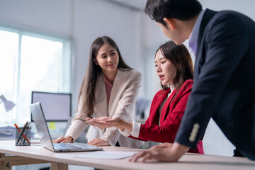 Three women and a man are sitting at a desk with a laptop open