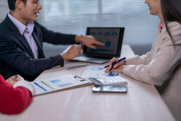 A man and a woman are sitting at a table with a laptop and a calculator