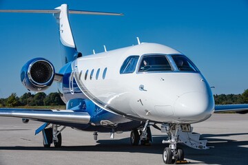 Detailed front view of a parked business jet under bright natural light. The image shows cockpit...