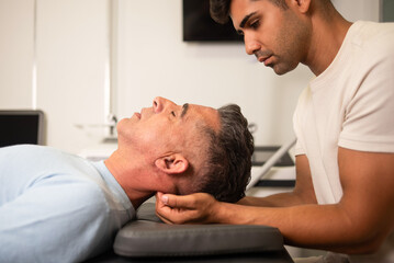 Professional young chiropractor helping get rid of neck pain to young man patient