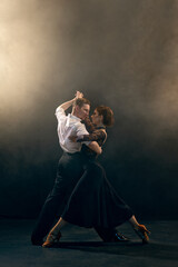 Argentine tango dancers in a passionate tango, striking a dramatic pose under evocative stage...