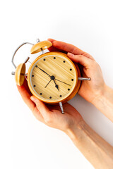 Hands are holding vintage wooden alarm clock with bells at seven o'clock. Morning routine. In time...