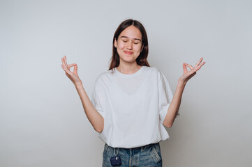 Young woman practicing mindfulness and meditation with a peaceful expression in a simple indoor...