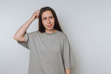 Young woman expressing confusion while thinking in a casual indoor setting with a neutral background