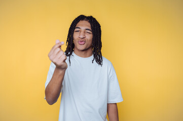 Young african american man in casual attire smiling and making a gesture against a bright yellow...