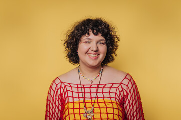 Bright yellow backdrop highlights a joyful young woman in a stylish red mesh top and colorful...