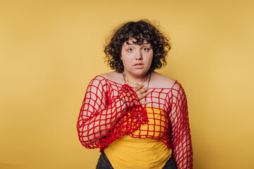 Young person expressing surprise in a vibrant yellow setting with a unique layered outfit