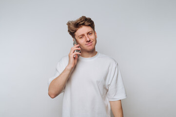Young man talking on the phone with a casual expression in a neutral background setting