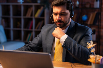 Indian businessman writes notes during online call, showing focus, learning, and remote teamwork