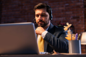 Indian businessman writes notes during online call, showing focus, learning, and remote teamwork