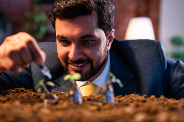 Businessman waters plant on coin stacks, showing concept of nurturing financial investment success