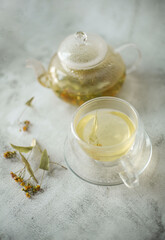 Brewed linden tea in teapot and cup on white background